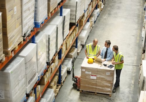 High angle view of supervisor discussing with workers at distribution warehouse